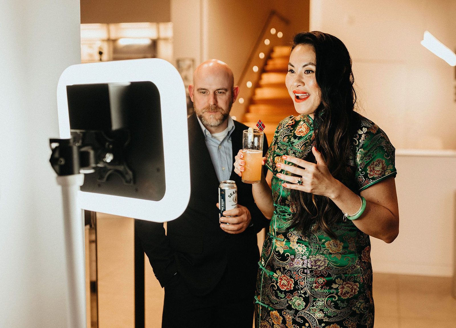 Un couple, verre à la main, se filme devant le vidéobooth pendant le cocktail