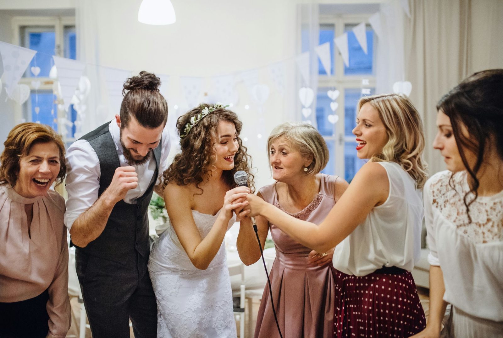 La mariée et sa grand-mère partagent un micro, entourées de leurs proches qui rient